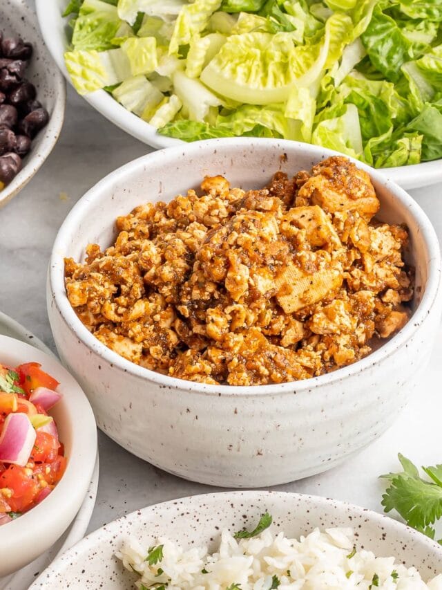 Bowl of tofu sofritas with burrito bowl toppings around it.