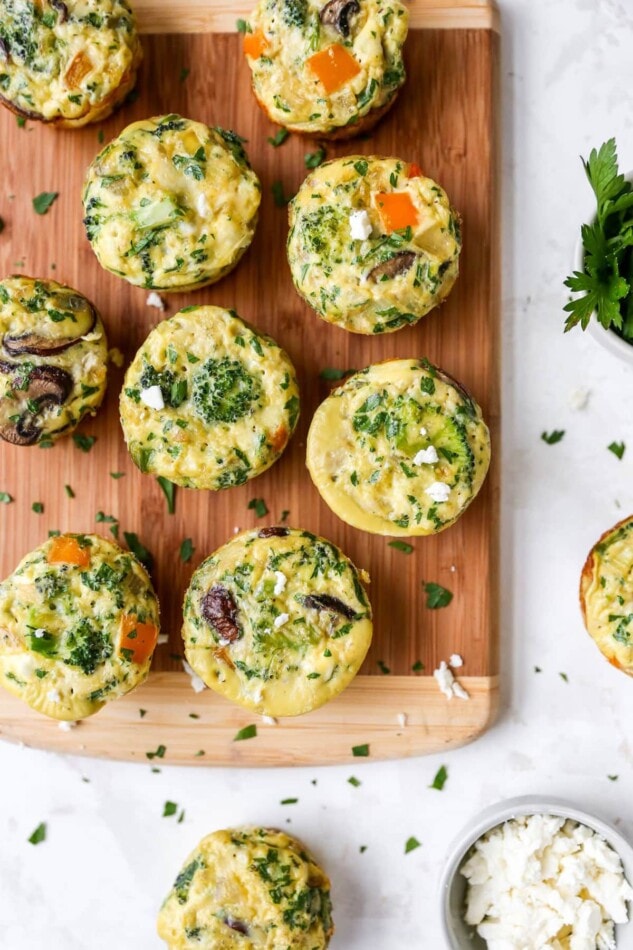 Baked egg and veggie cups on a wood cutting board.