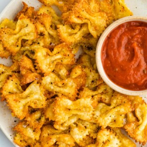 Pasta chips on a plate with a small bowl of marinara for dipping