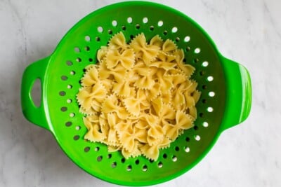 Drained pasta in a green colander.