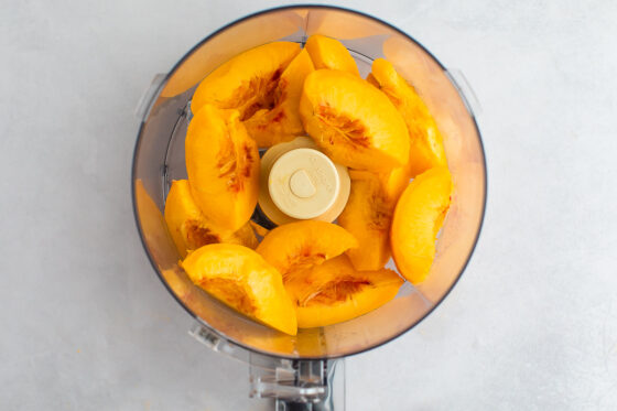 Blanched, peeled and sliced peaches in a food processor.