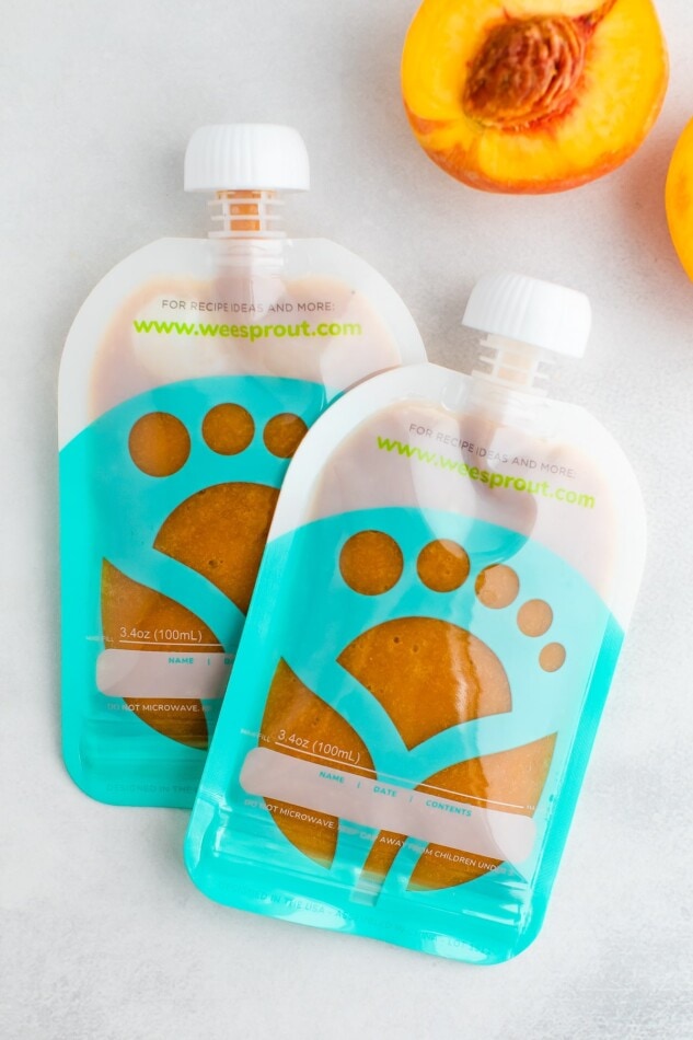 Two reusable pouches for babies filled with peach puree.