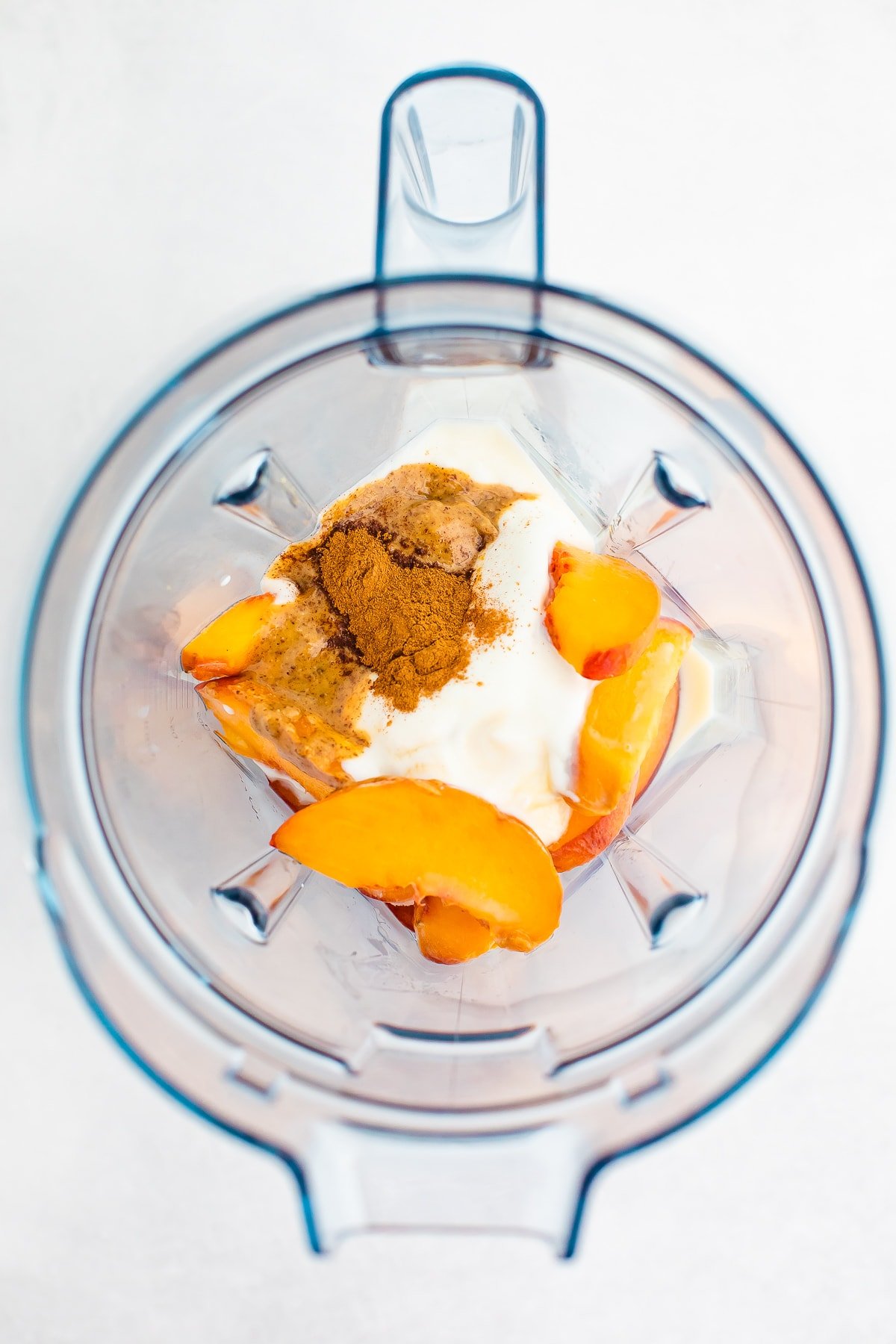 Blender with cinnamon, almond butter, yogurt, almond milk and frozen peaches.