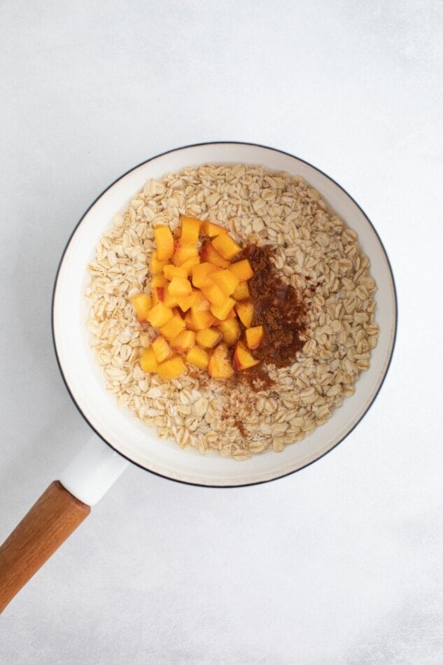 Pot with oats, peaches, coconut sugar and cinnamon.