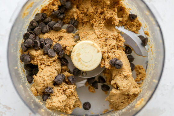 Protein cookie dough in food processor with chocolate chips on top.