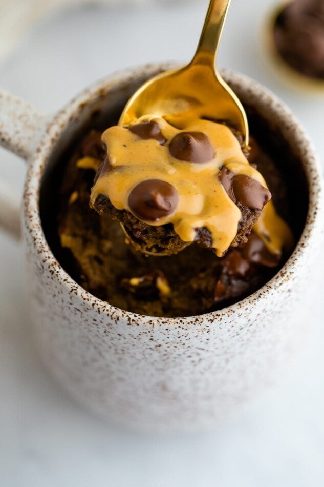 Spoon taking a bite out of the chocolate peanut butter mug cake.