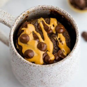 Chocolate protein mug cake drizzled with peanut butter and topped with chocolate chips.