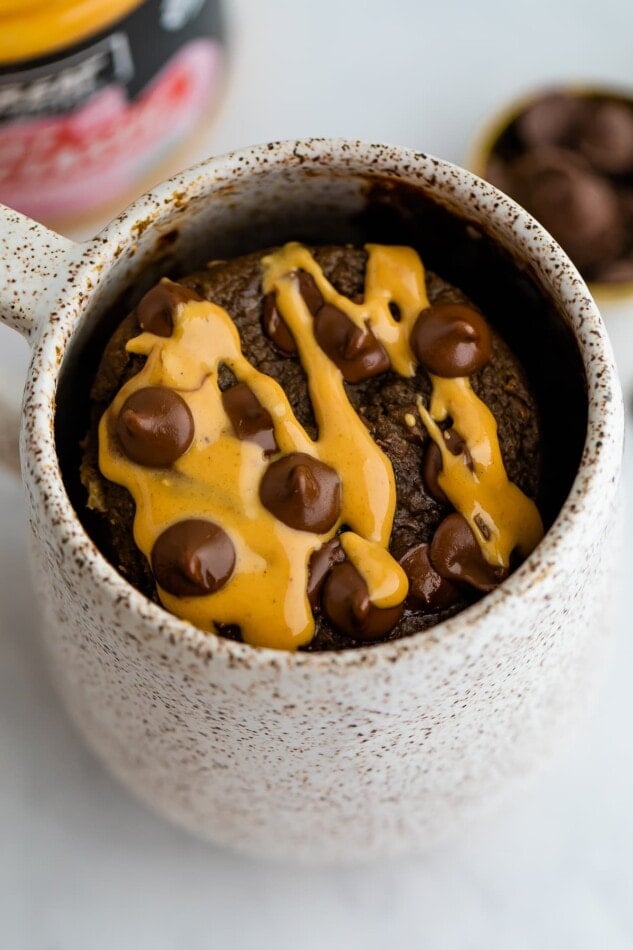 Chocolate protein mug cake drizzled with peanut butter and topped with chocolate chips.
