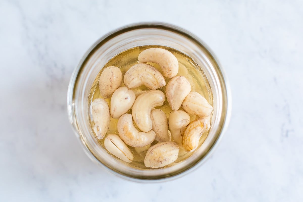 Jar of cashews soaking in water.
