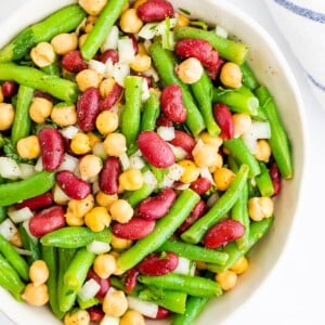 Serving bowl with three bean salad, a salad made with chickpeas, kidney beans, onion and green beans.