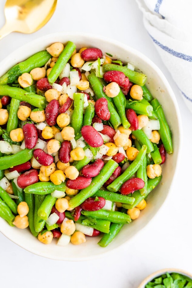 Serving bowl with three bean salad, a salad made with chickpeas, kidney beans, onion and green beans.
