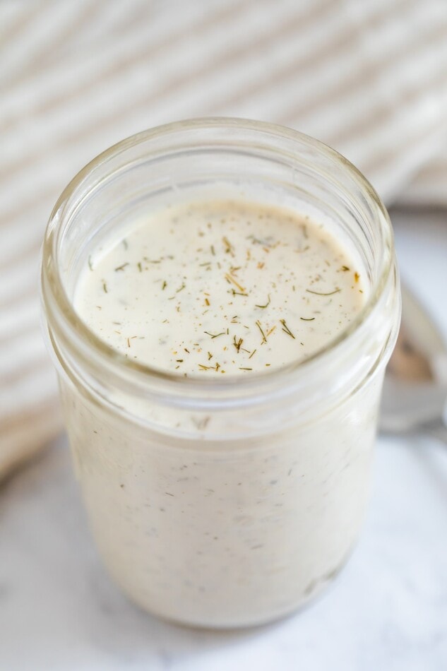 Mason jar of vegan ranch dressing. A spoon is to the side.