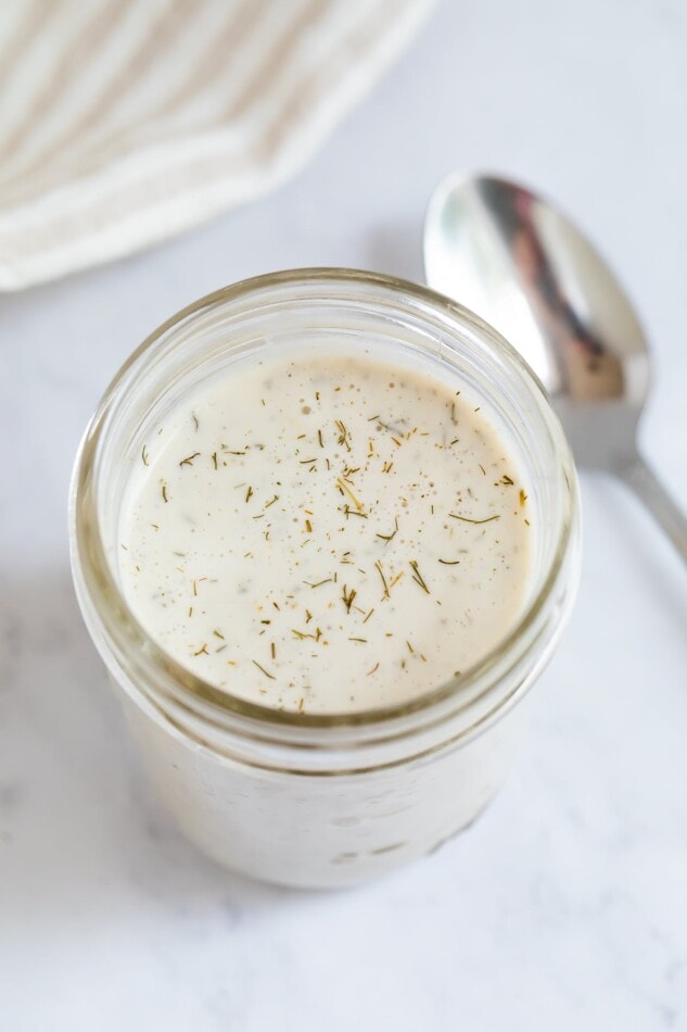 Mason jar of vegan ranch dressing. A spoon is to the side.