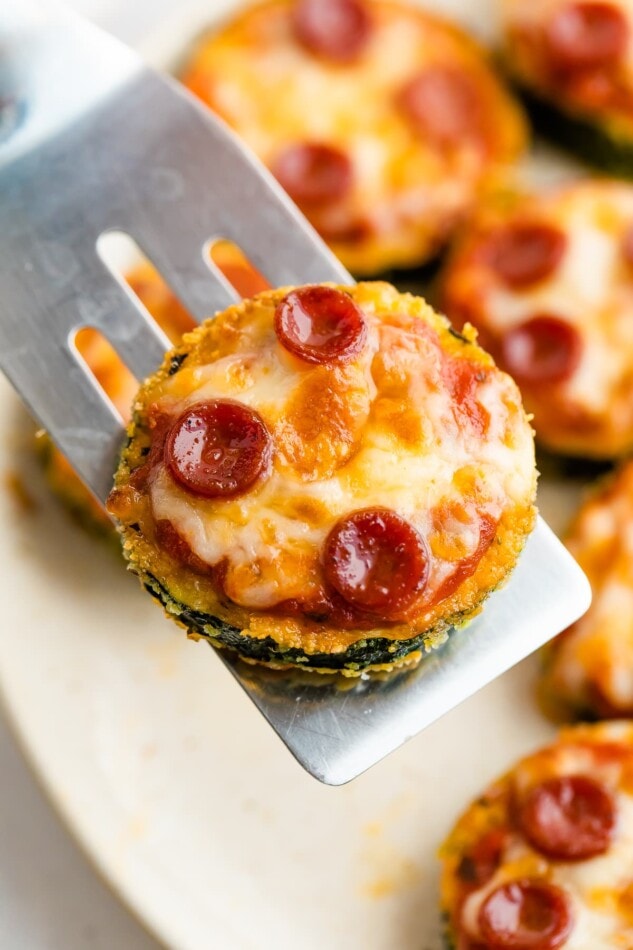 Spatula holding a zucchini pizza bite.