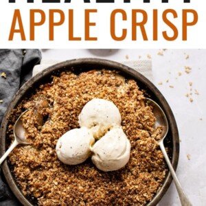 Apple crisp in a pan topped with three scoops of ice cream. A couple spoons are in the pan.