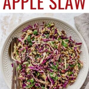 Plate with serving utensils with an apple slaw made with cabbage and quinoa.