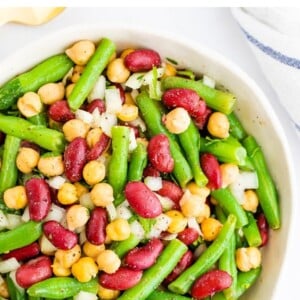 Serving bowl with three bean salad, a salad made with chickpeas, kidney beans, onion and green beans.