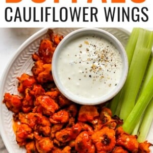 Plate of buffalo cauliflower wings served with vegan cashew ranch and celery sticks.