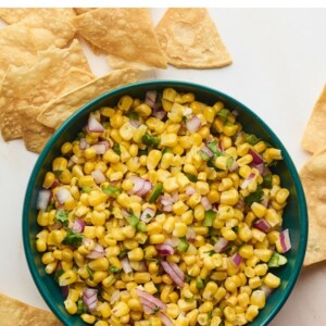 Bowl of corn salsa surrounded by tortilla chips.