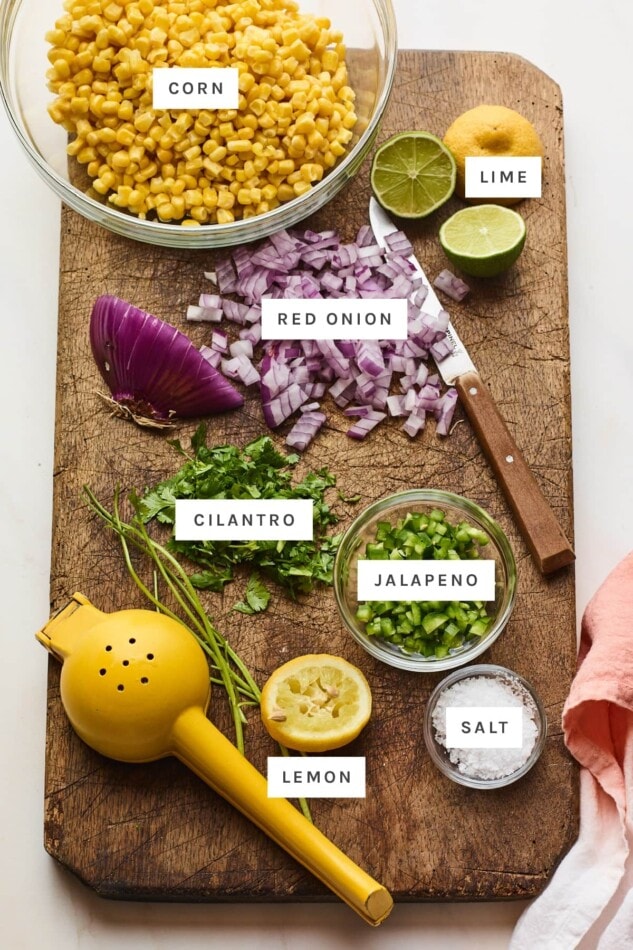 Ingredients measured out to make corn salsa: corn, lime, onion, cilantro, jalapeno, lemon and salt.