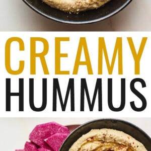 Creamy hummus with olive and spices on top in a black serving bowl with sliced vegetables for dipping plated around the bowl.