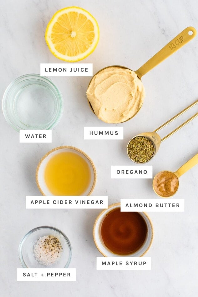 Ingredients measured out for hummus dressing: lemon, hummus, water, oregano, apple cider vinegar, almond butter, maple syrup, salt and pepper.