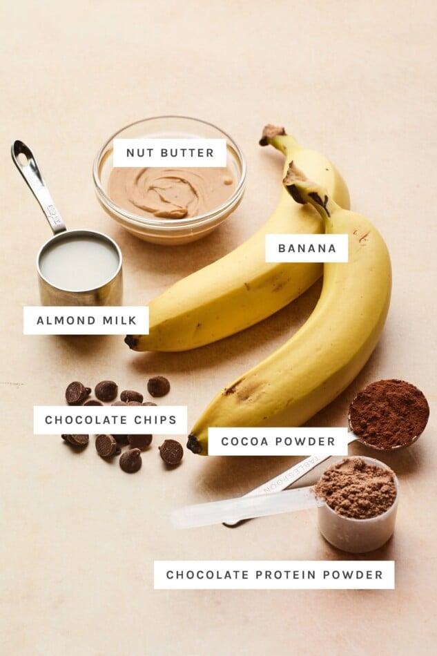 Ingredients measured out to make chocolate protein ice cream: nut butter, banana, almond milk, cocoa powder, chocolate protein powder and chocolate chips.