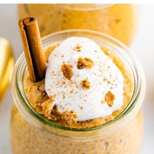 Pumpkin chia pudding in a tulip weck jar, topped with coconut whipped cream, granola and a cinnamon stick.