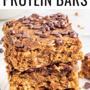 A stack of protein pumpkin bars on a white plate with chocolate chips sprinkled around.