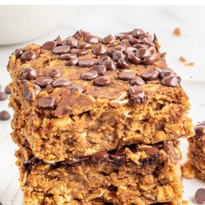 A stack of protein pumpkin bars on a white plate with chocolate chips sprinkled around.