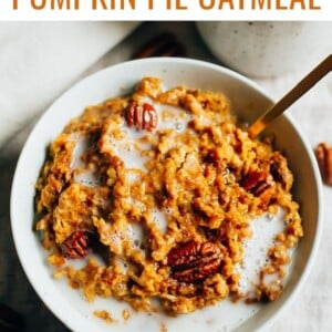 Bowl of pumpkin pie oatmeal topped with almond milk and pecans.