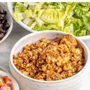 Bowl of tofu sofritas with burrito bowl toppings around it.