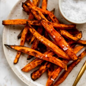 Overhead shot of a plate with fries, there is a ramekin of salt in focus.