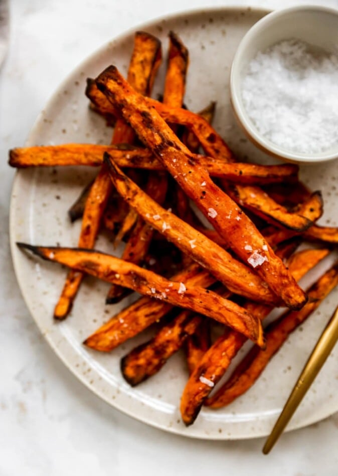 Overhead shot of a plate with fries, there is a ramekin of salt in focus.