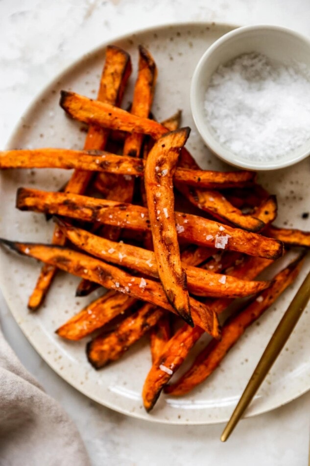 Overhead shot of a plate with fries, there is a ramekin of salt in focus.