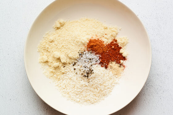 Overhead shot of a bowl with almond meal, coconut, paprika, cayenne, garlic, sea salt and black pepper ready to be combined.
