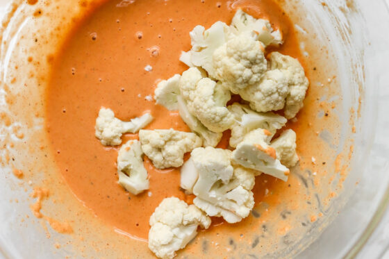 Cauliflower florets in a bowl of spiced batter before being coated in the batter.