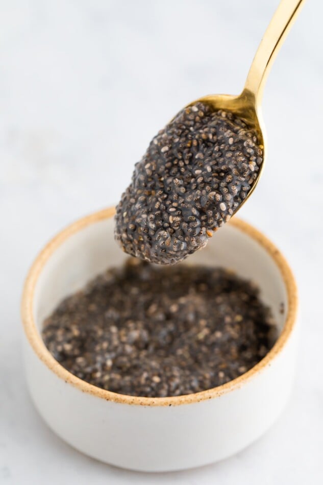 A close up of a spoon with chia seed egg above a ramekin.