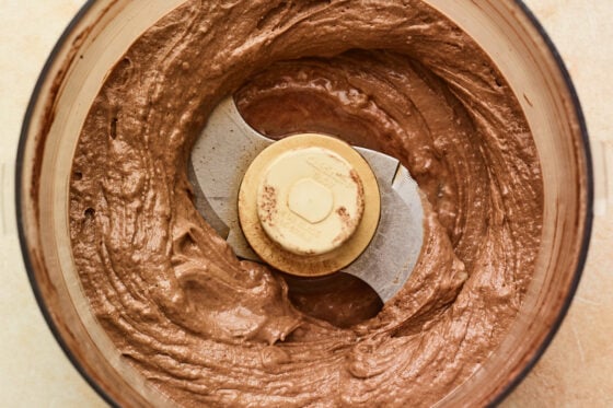 Food processor with blended chocolate protein ice cream base.
