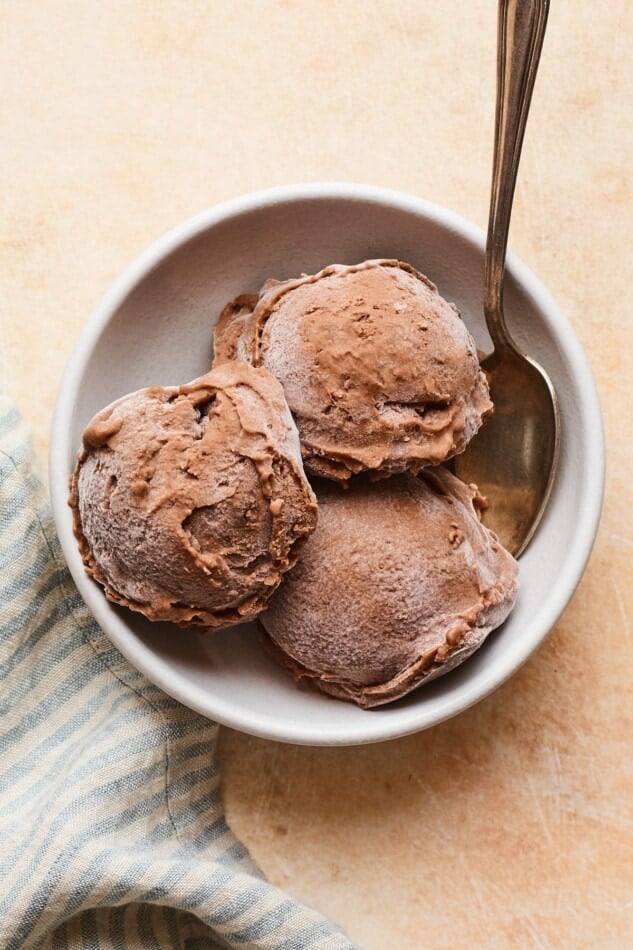 Bowl and spoon with three scoops of chocolate protein ice cream.