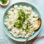 Overhead shot of a bowl of cilantro rice with a serving spoon.