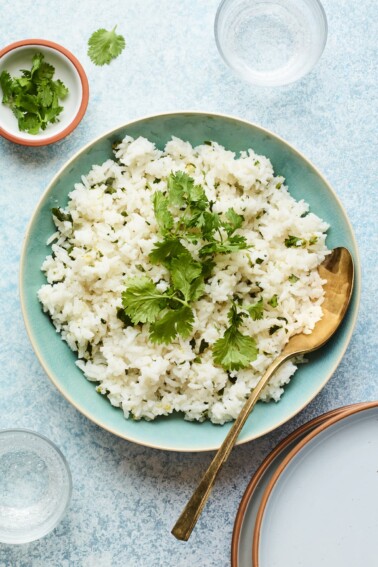 Overhead shot of a bowl of cilantro rice with a serving spoon.