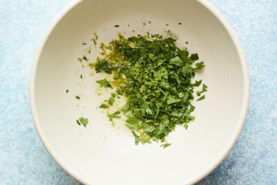Overhead shot of chopped cilantro with lime juice and zest in a bowl.