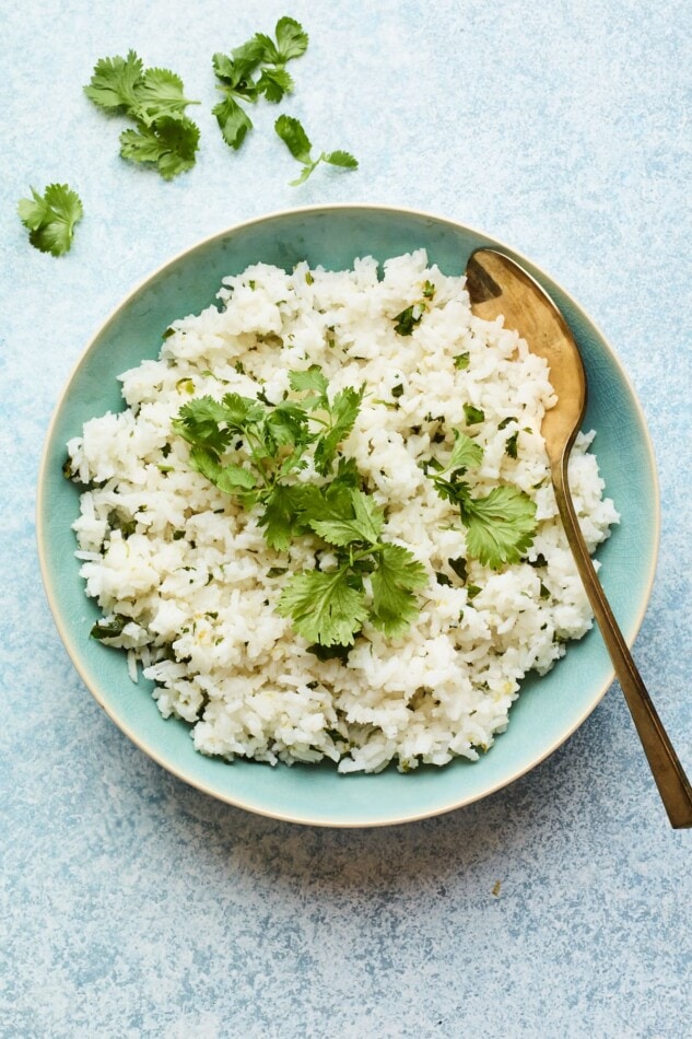 Overhead shot of easy cilantro rice in a serving bowl with a serving spoon.