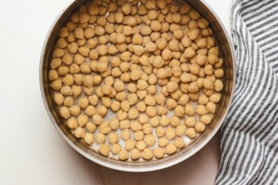 Chickpeas soaking in water in a sauce pan.