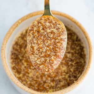 A close up of a spoon with flax egg over a ramekin of flax egg.
