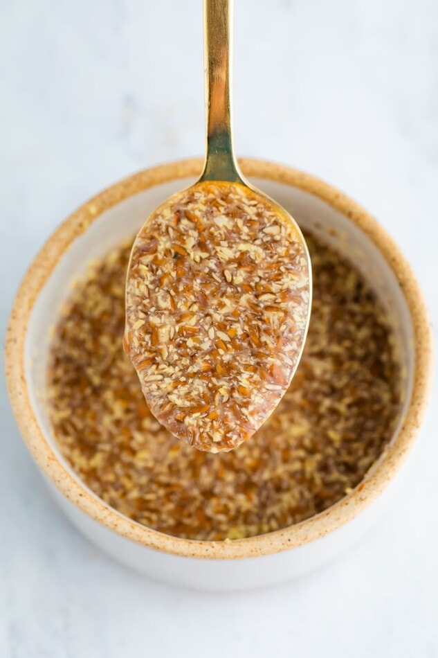 A close up of a spoon with flax egg over a ramekin of flax egg.