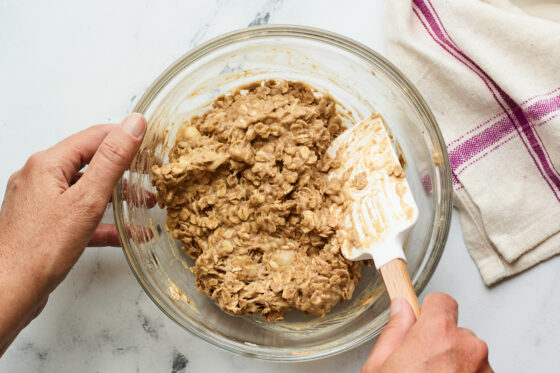 Mixing bowl of protein no bake cookie mixing being mixed with a spatula.