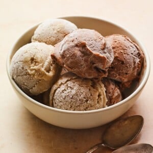 Large bowl of several scoops of chocolate and vanilla protein ice cream. Two spoons are beside the bowl.