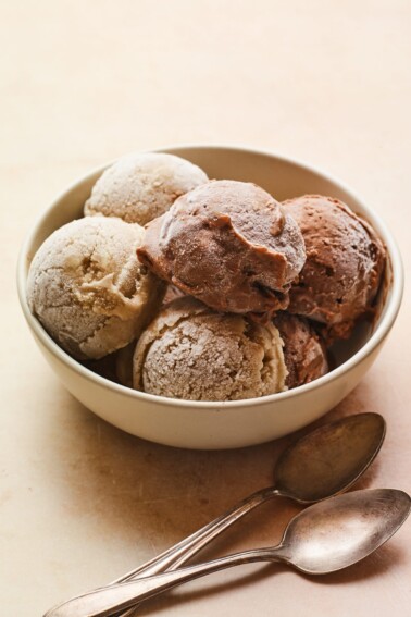 Large bowl of several scoops of chocolate and vanilla protein ice cream. Two spoons are beside the bowl.